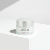 A jar of Missha Time Revolution The First Essence Cream placed on a white surface with a shadow falling across the frame.